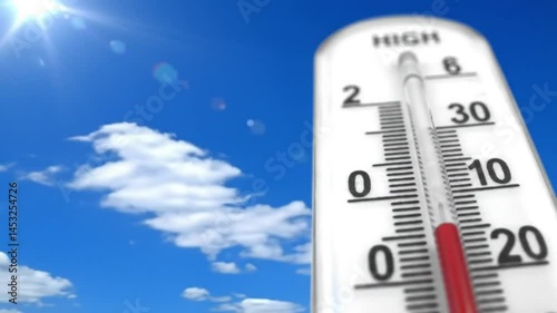 A thermometer showing a high temperature against a blue sky with fluffy white clouds outside view shot