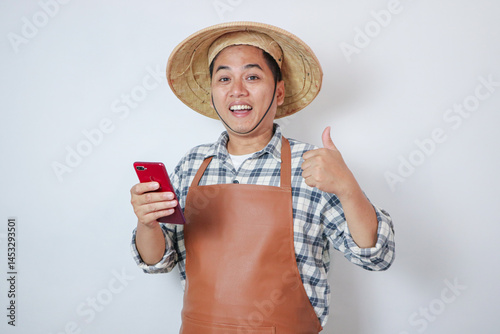 Young farmer smiling and give one thumb up whit smartpone photo