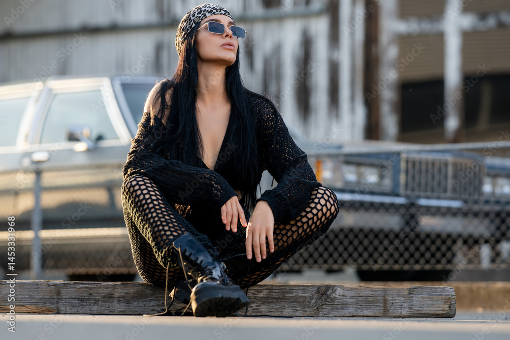Fashion street. Sexy fashion woman sitting outdoor. Dangerous areas. Fashionable brunette in black jacket bandana and sunglasses in urban style. Lifestyle of female hipster. Casual dress style.