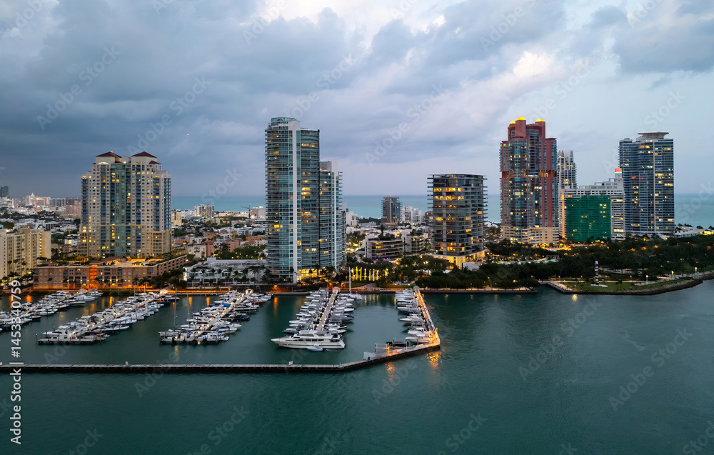 Fototapeta premium Miami Beach sunset aerial view. Downtown Miami skyline at dusk. South Beach neon lights at night. Tropical Miami waterfront panorama. Ocean Drive Art Deco buildings. Aerial view of Miami coastline.