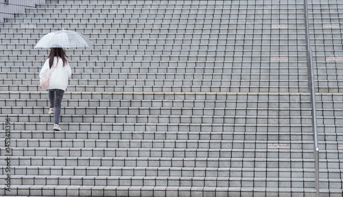 雨の日に傘を持って商業施設の階段を上る女性の姿