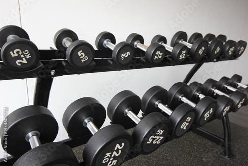 a rack of black dumbbells of varying weights in a gym setting