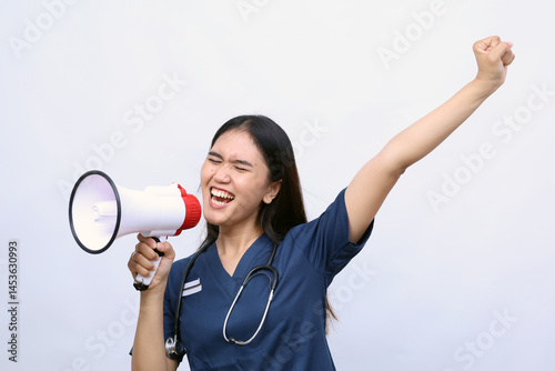 Young Asian woman doctor on white studio background speaking talking in loudspeaker. Make announcement in speaker. Medicine, attention, healthcare concept.Holding megaphone