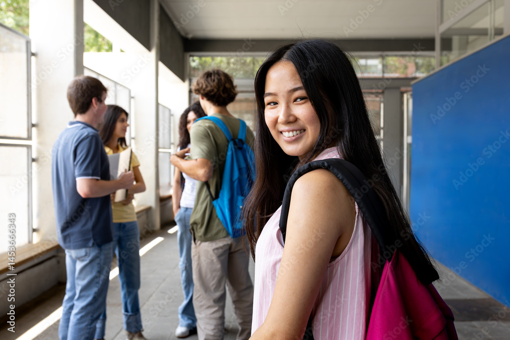 Obraz premium Happy asian student smiling in university hallway with friends