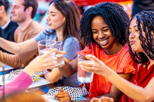 Multiethnic friends toasting, enjoying together a weekend at the bowling alley