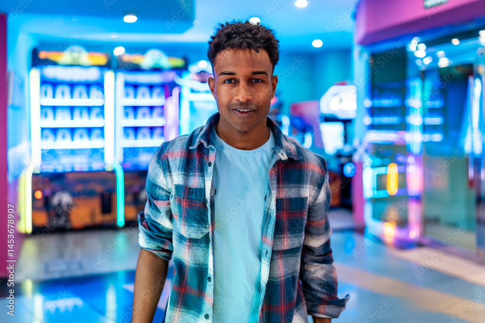 Young man enjoying weekend fun at the arcade with claw machines and games
