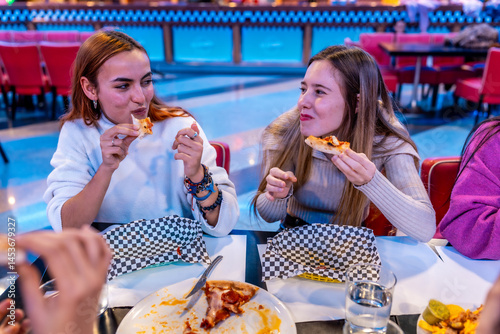 Obraz na płótnie Cheerful young women eating pizza at bowling alley restaurant w salonie