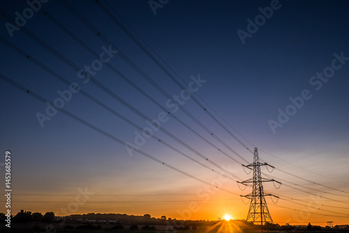 Electricity pylons and high voltage power lines at sunrise in countryside