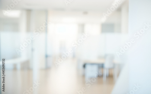 Blurred office interior with desks and partitions in a bright white space.