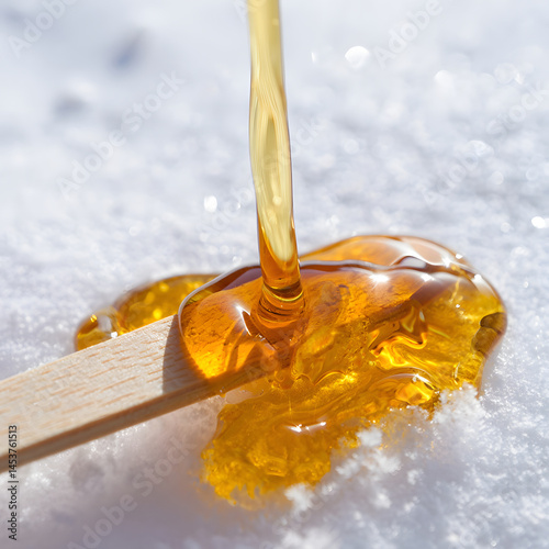 Close-up of tire d'érable hardening on snow, golden syrup texture and wooden stick in focus, soft snowy background blur