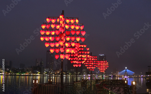The Love Bridge in Da Nang, Vietnam, adorned with heart-shaped lanterns. This pedestrian bridge is a popular spot for couples to attach love locks, symbolizing their affection, similar to other 