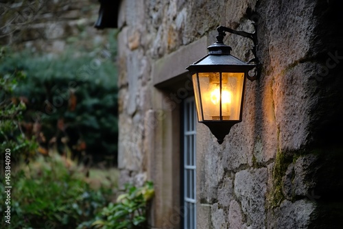 antique gas lamp glowing outside a stone cottage