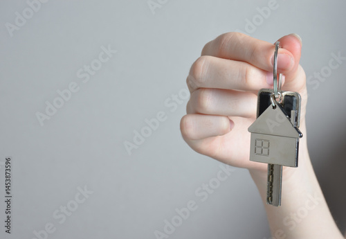 Metal keychain in the shape of a house and a key in hands.