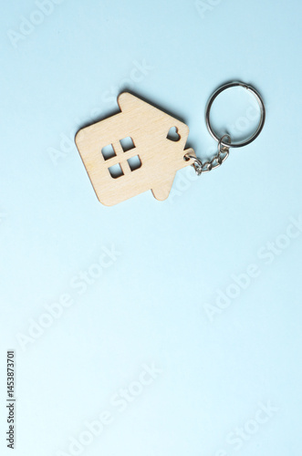 Wooden keychain in the shape of a house. Blue background.
