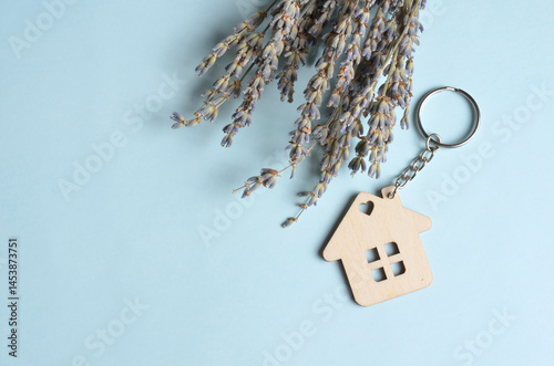 Wooden keychain in the shape of a house and lavender. Blue background.