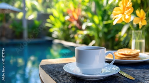 Serene breakfast setting by the poolside with coffee, pancakes, and vibrant tropical plants