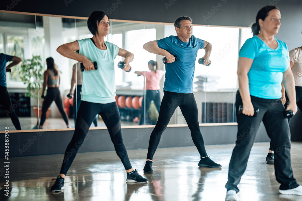 Fototapeta premium Multiethnic fitness enthusiasts lifting dumbbells in sync. Focus on wellness, teamwork, and strength