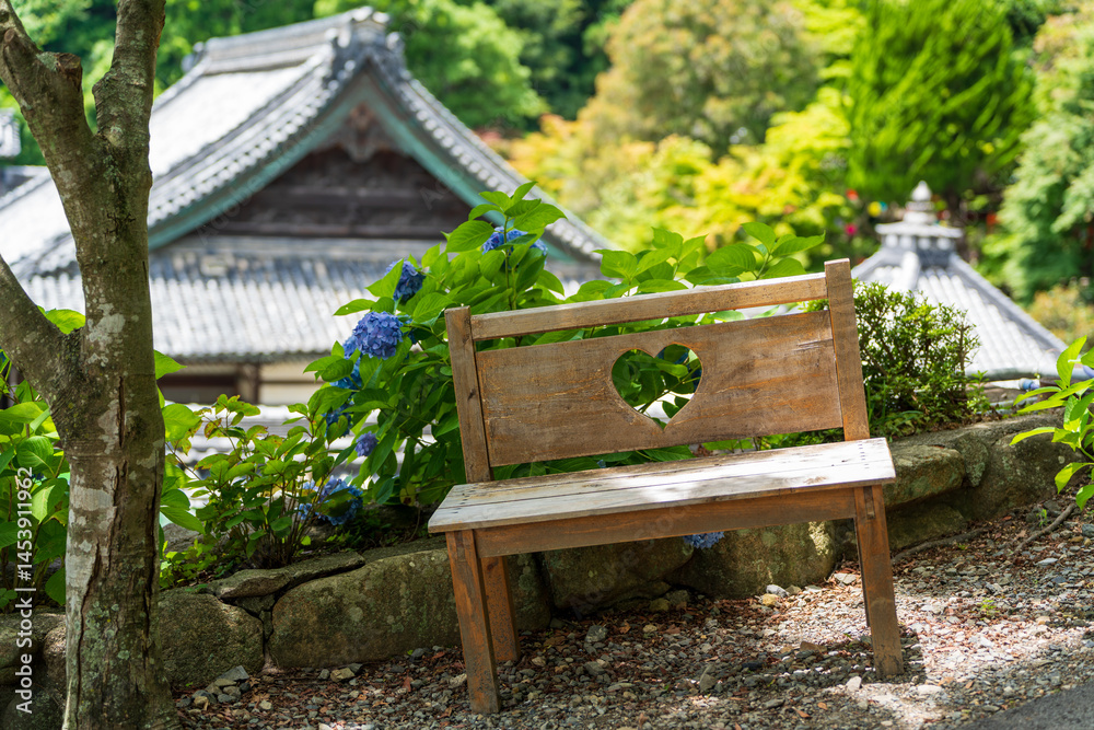 Naklejka premium Wooden Bench with Heart-Shaped Window Cutout Amongst Hydrangeas at Yanagidani Kannon Yokoku-ji Temple, Kyoto.
