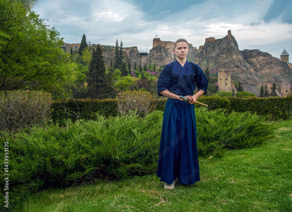 Young man in Japanese kimono kendo fighter on stunning background with fortress