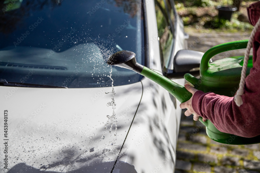 Auto abwaschen mit einer Gießkanne und viel Wasser