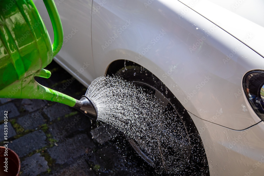 Autoreifen abwaschen mit einer Gießkanne und viel Wasser