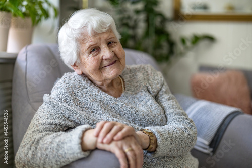 Konstfotografi Elderly woman at her home sitting in armchair and looking at camera