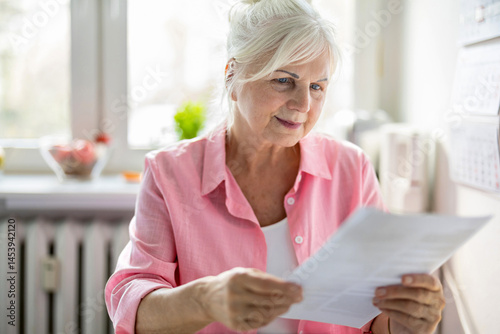 Senior woman looking through financial documents at home 

