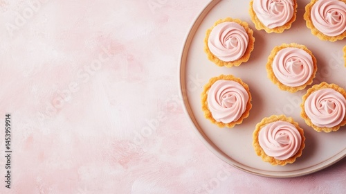 Delicious cupcakes with swirls of pink frosting on a light beige plate against a soft pink background