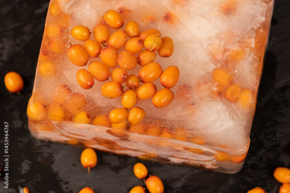orange sea buckthorn berries during deep freezing, close up and scattered melted berries