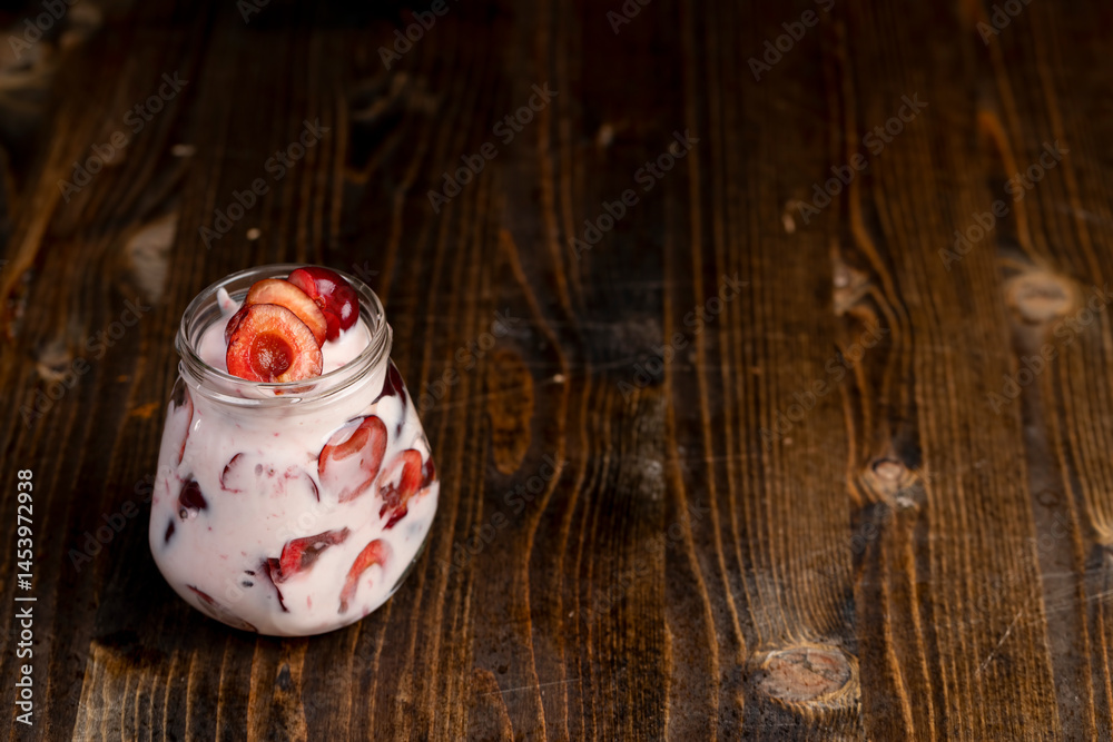 yogurt with cherry and berry slices, glass jar with cherry yogurt with fresh red cherries