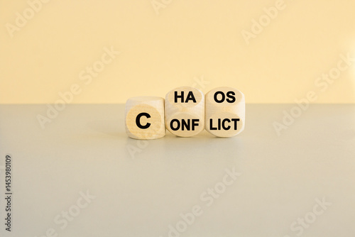 From conflict to chaos symbol. Concept words Conflict and Chaos on wooden cubes. Beautiful gray table beige background. Business Conflict and Chaos concept.