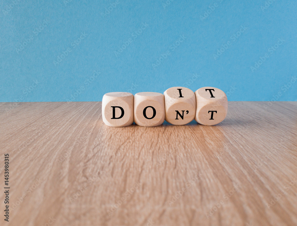Doubt, uncertainty. Turned wooden cubes with words DO IT or DON'T on the table over blue background. Concept of complexity of the choice