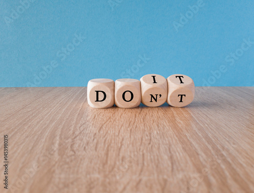 Obraz na płótnie Doubt, uncertainty. Turned wooden cubes with words DO IT or DON'T on the table over blue background. Concept of complexity of the choice w salonie