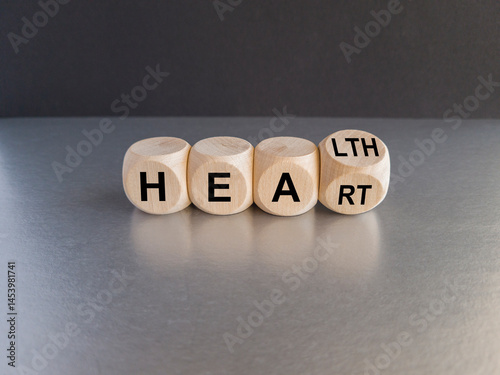 Obraz na płótnie Dice form the words 'heart' and 'health'. Symbol for a heart checkup. Beautiful gray table, black background. Business and medical concept. w salonie