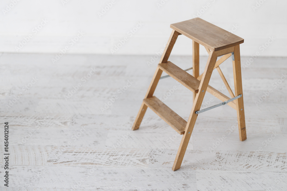 Wooden step ladder on light wooden floor in minimalist setting
