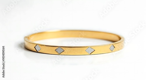 White background close-up of sleek gold bangle with triangle accents.