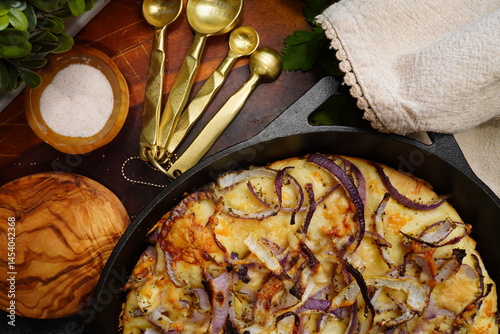 Cooking a Fugazetta which is an Argentine style stuffed pizza with cheeses and herbs. Stuffed pizza in a cast iron pan with layers of cheese, garlic, onions and herbs stuffed between layers of dough.