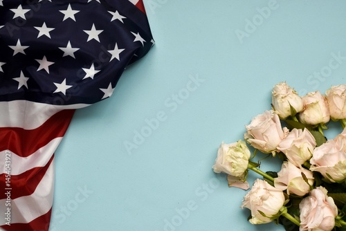 Concept of U.S Independence day or Memorial day. National flag over blue background with white roses. Symbol of America. Banner with copy space, flat lay.