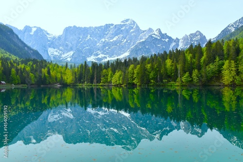 Obraz na płótnie View of mountain Mangart above lago di fusine inferiore with a forest at the lake shore in municipality of Tarvisio, Italy w salonie