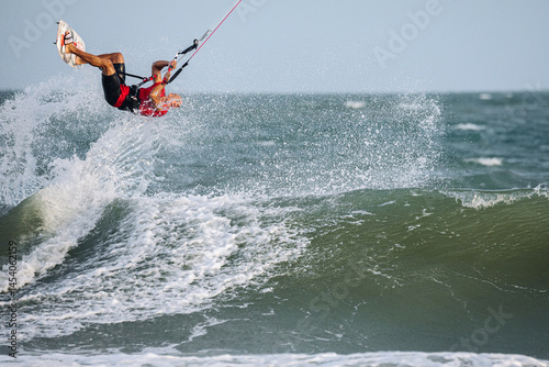 Man kitesurfing on ocean waves at tropical beach