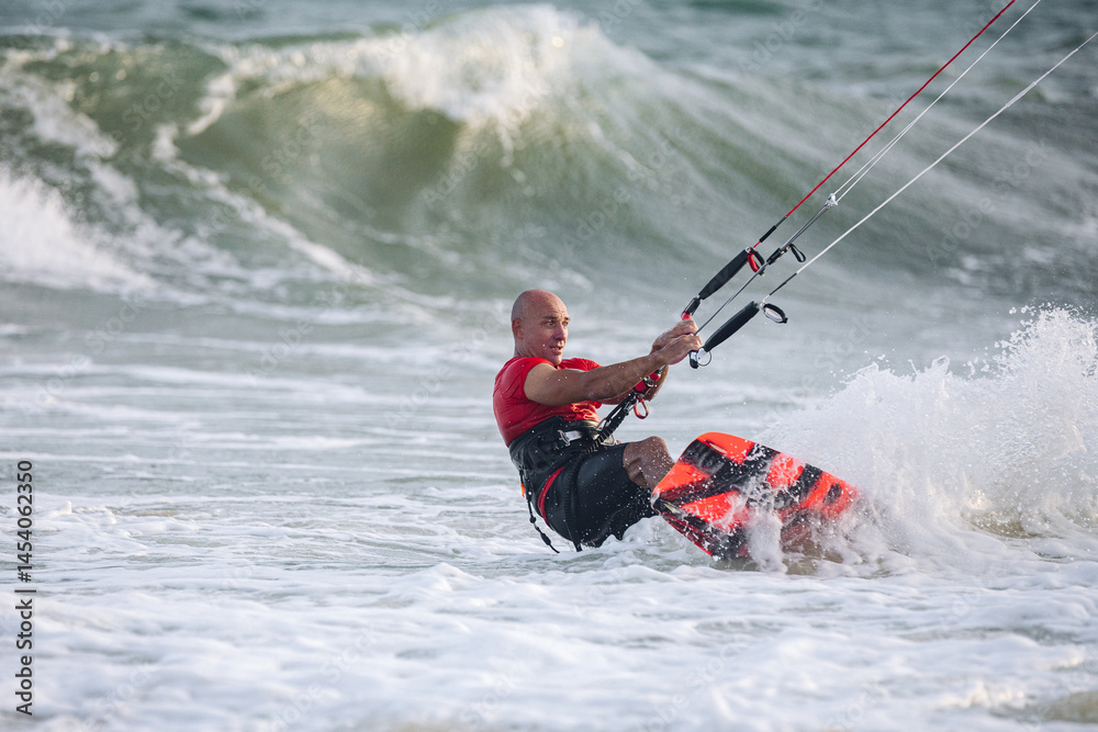 Naklejka premium extreme kitesurfer riding a kite on the waves in the sea