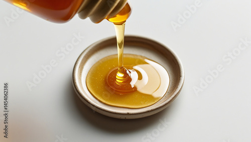 Close-up shot of honey being drizzled onto a small ceramic plate, all elements fully within frame, no parts cut off, no blur, sharp detail across the full surface, warm golden tones, flat top-down per