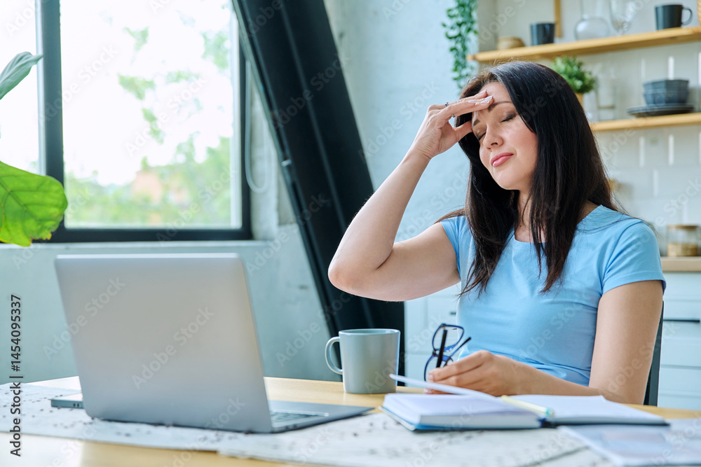 Sad stressed woman sitting at home at table with computer