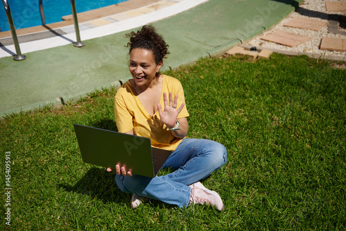 Woman Waving During Laptop Video Call Outdoors on Sunny Day
