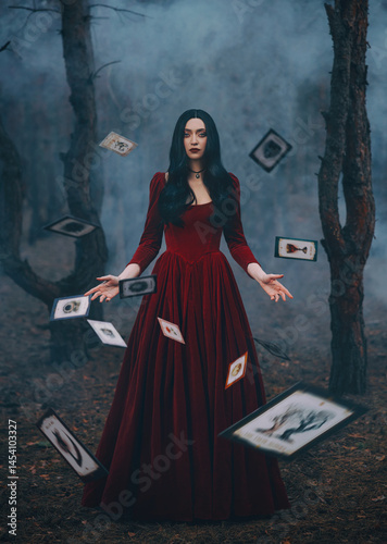 Art photo real person Gothic girl witchgirl stands surrounded by falling levitating blurred cards sheets of paper. night dark forest. Fantasy Woman red dress Black long hair sexy strong beauty face