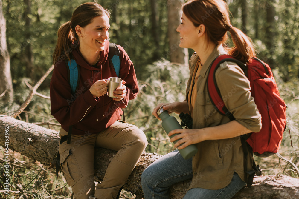 Friends sharing laughs and drinks while enjoying a peaceful hike in a lush forest during a sunny day