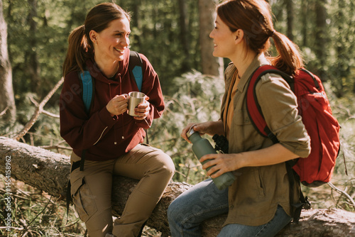 Obraz na płótnie Friends sharing laughs and drinks while enjoying a peaceful hike in a lush forest during a sunny day w salonie