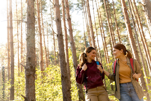 Obraz na płótnie Friends enjoying a joyful hike through a sunlit forest during a serene afternoon in autumn w salonie