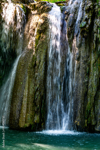 Hidden waterfall cascading through lush green forest in a serene natural oasis