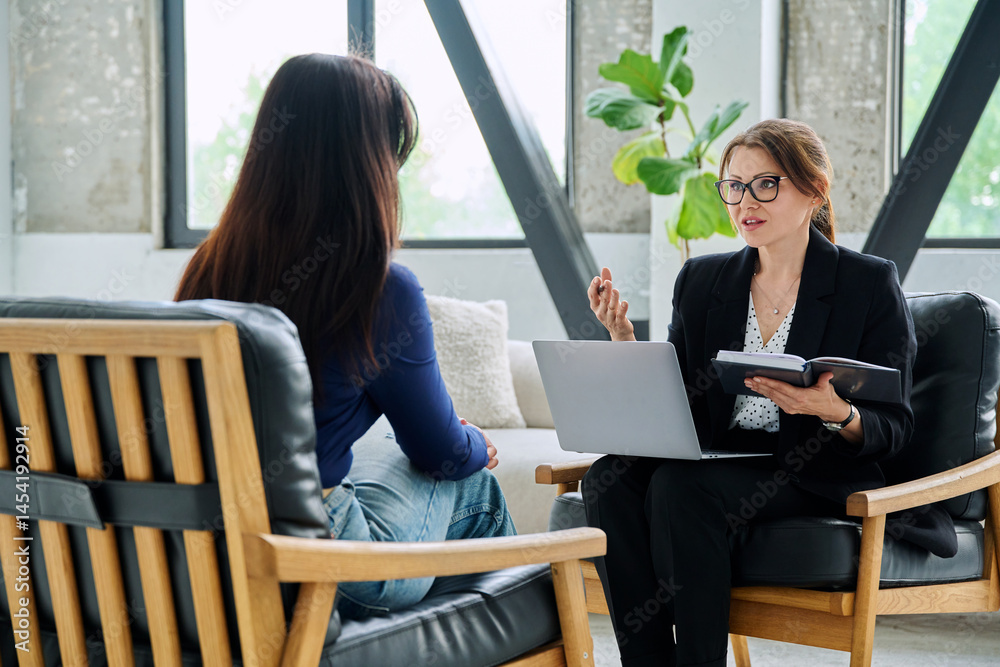 Female journalist, employer interviewing working with woman sitting together in office